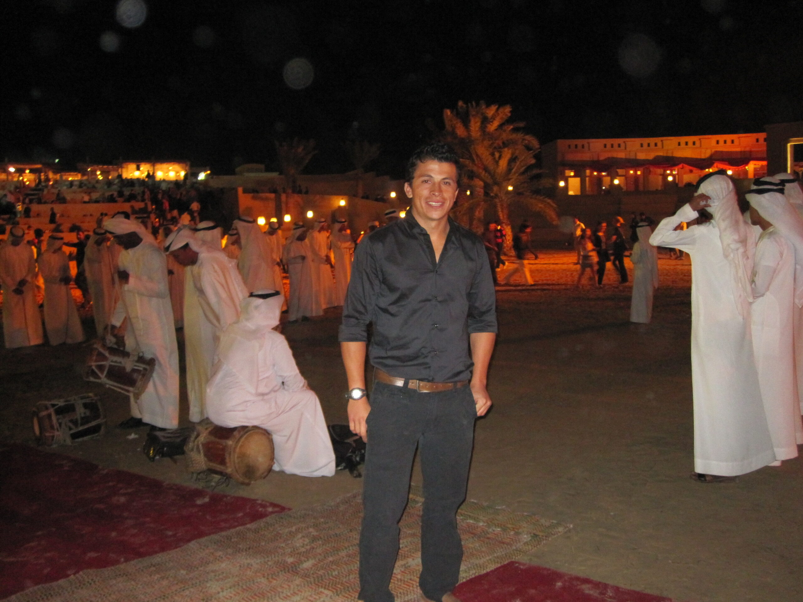 A man standing in a festive outdoor setting at night.